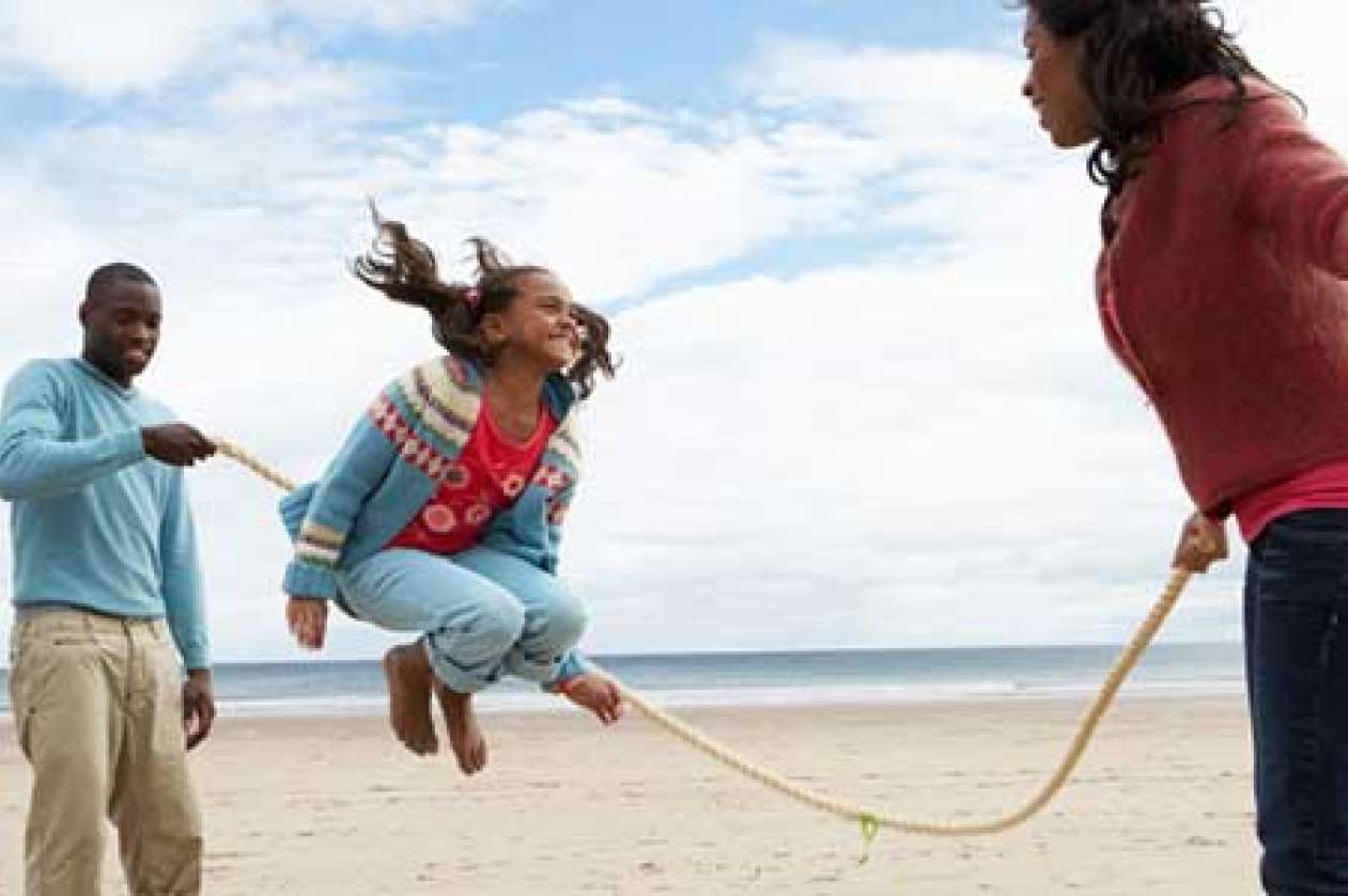 Young girl skipping rope on the beach
