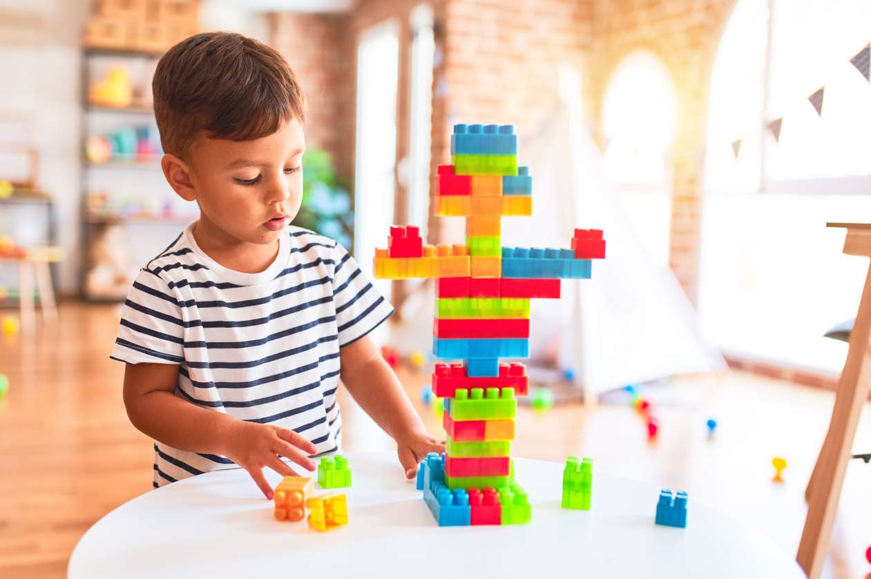 A young boy builds a tower made of blocks.