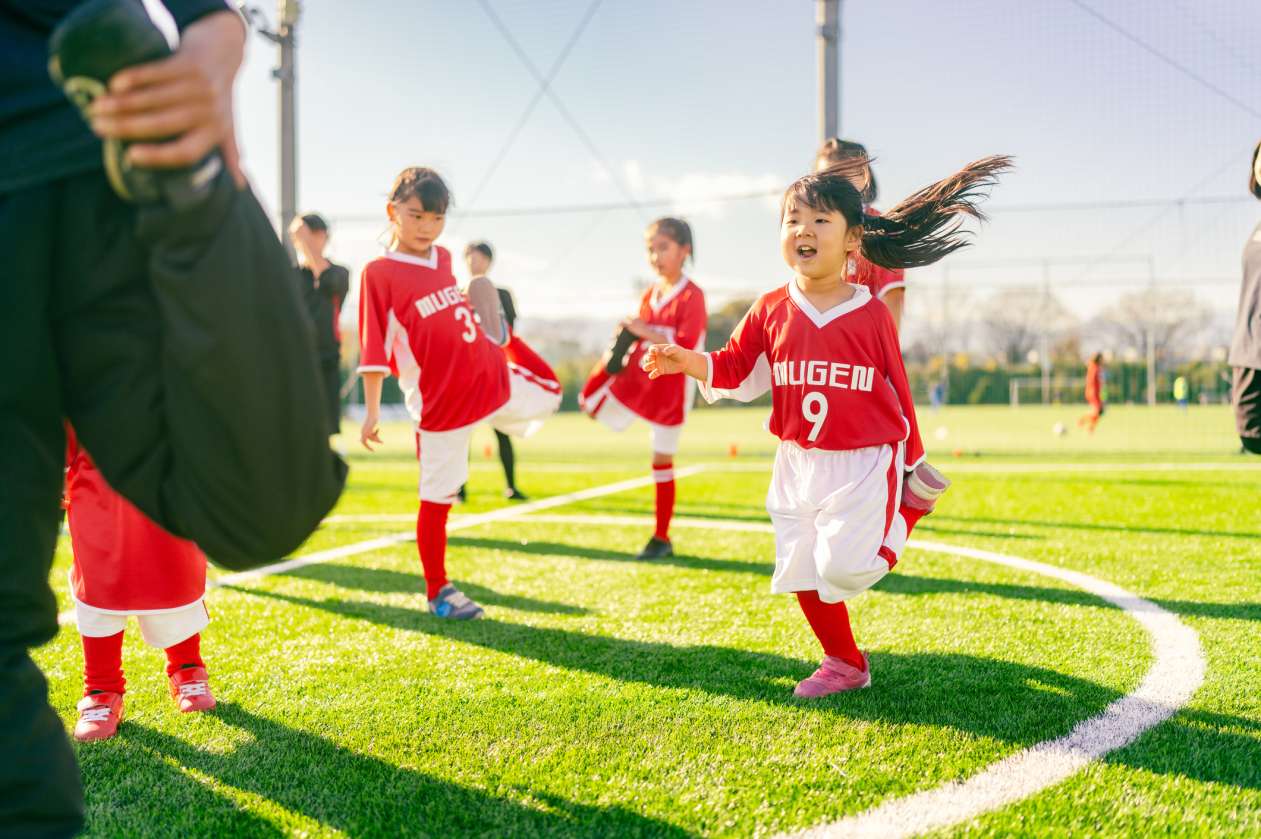 Led by their coach, a children's soccer team stretches before a game.