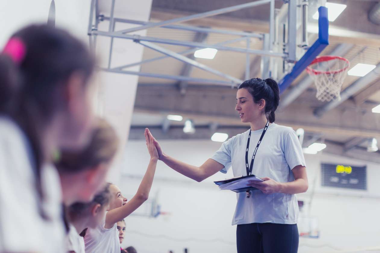 A coach high-fives athletes on her volleyball team.