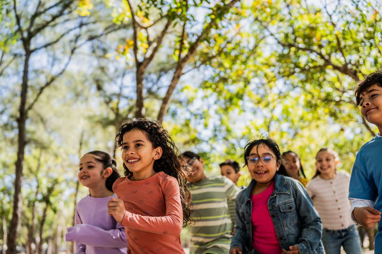 A group of school-age children run outside on a spring day.