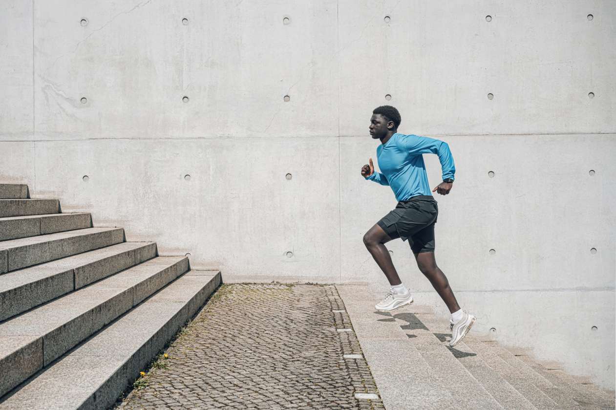 An elite athlete runs up a flight of stairs outdoors.