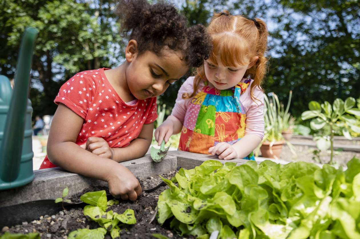 Two young girls garden outside at a childcare centre.