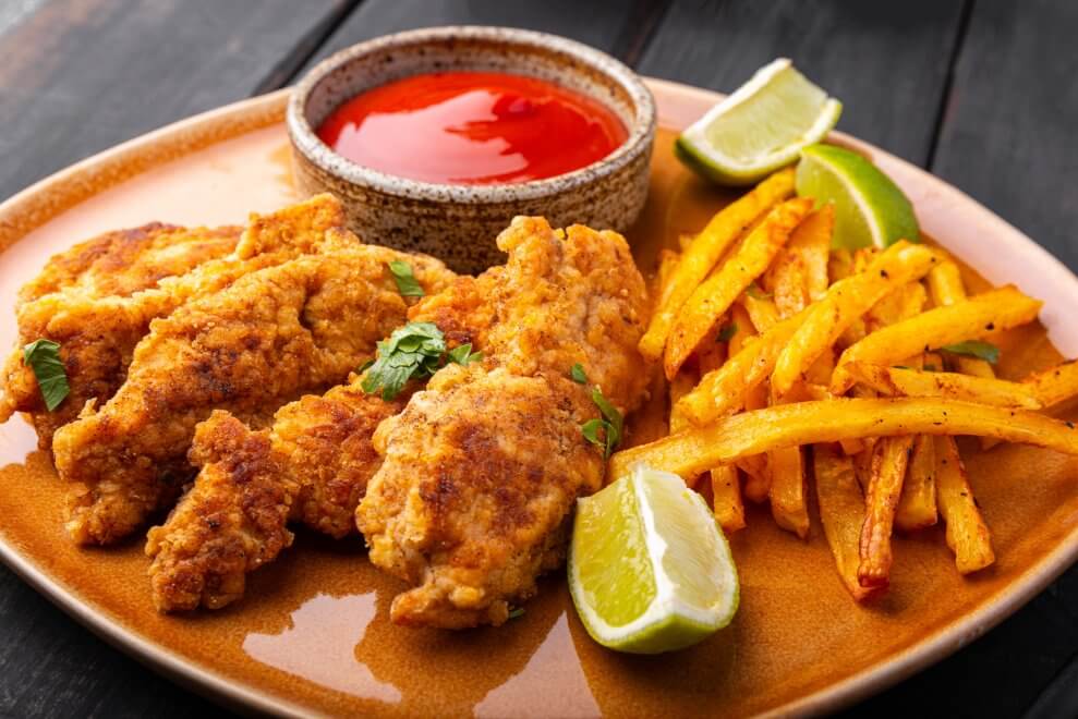 Chicken tenders on a plate with fries and ketchup