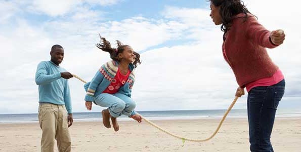 Young girl skipping rope on the beach