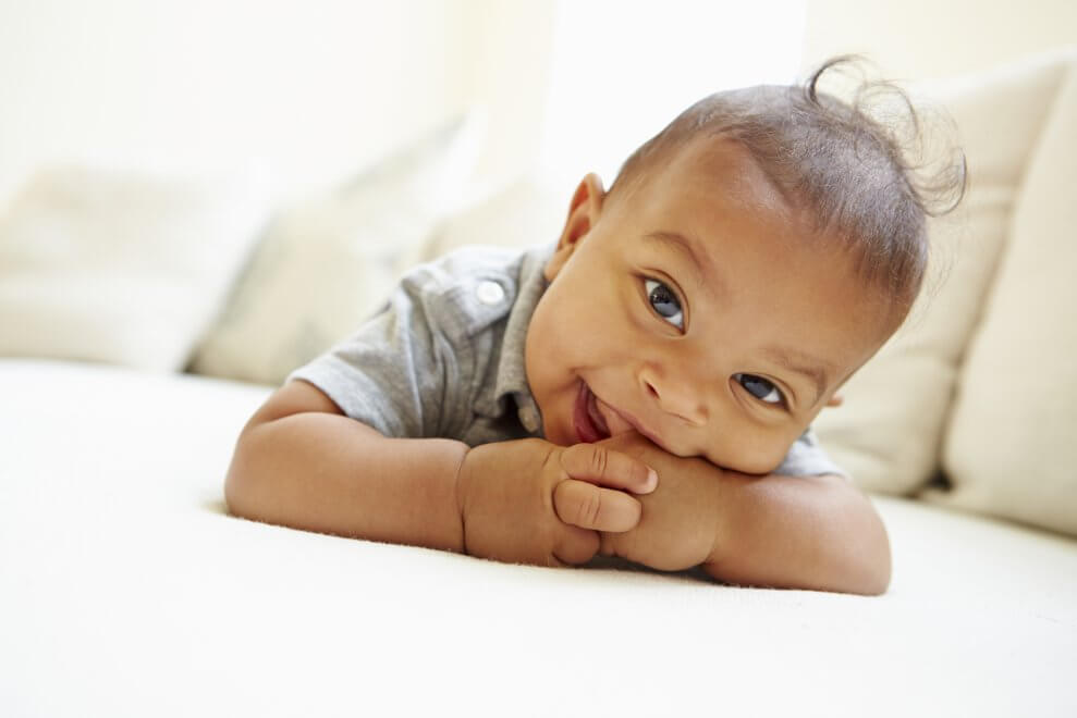 A baby lies on his stomach, smiling.