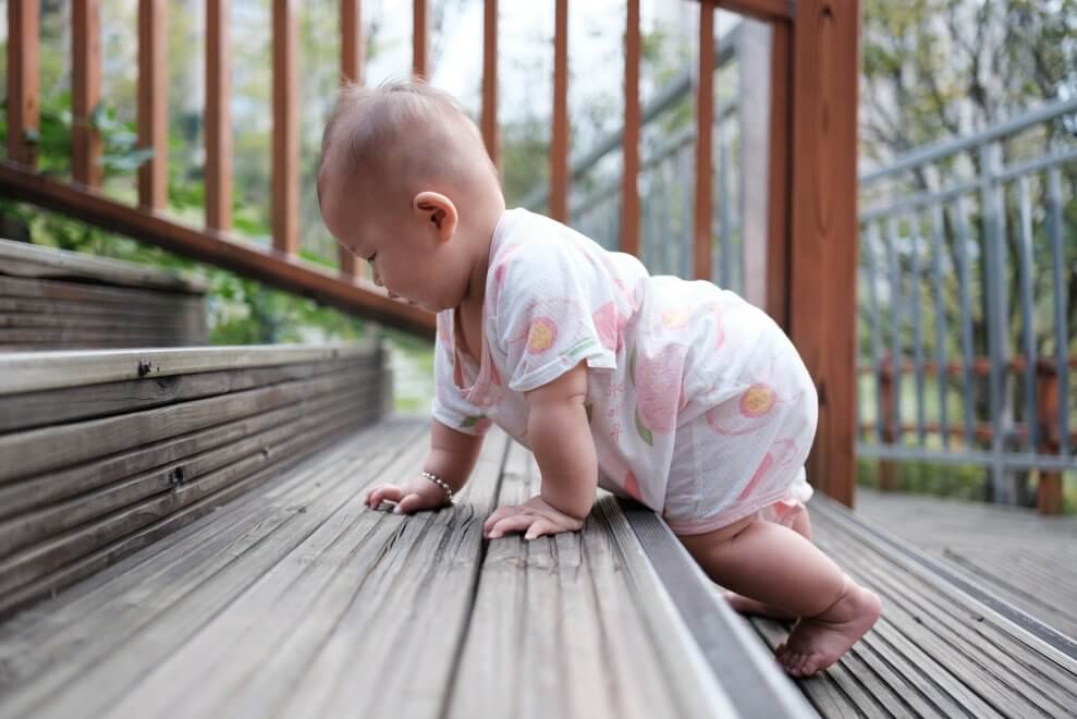 A baby crawls up a set of outdoor stairs.