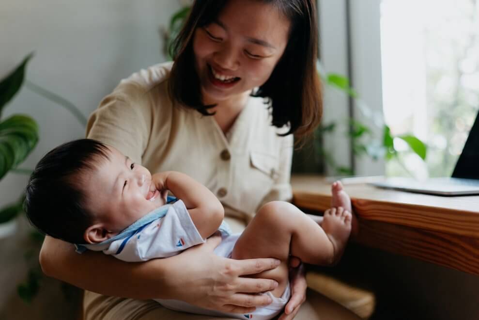 A mom rocks her baby as he smiles up at her.
