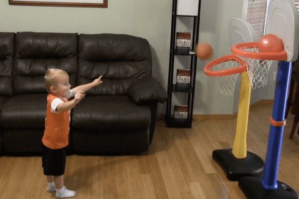Titus the toddler shoots two balls into two kid-sized basketball nets at the same time—and scores both.