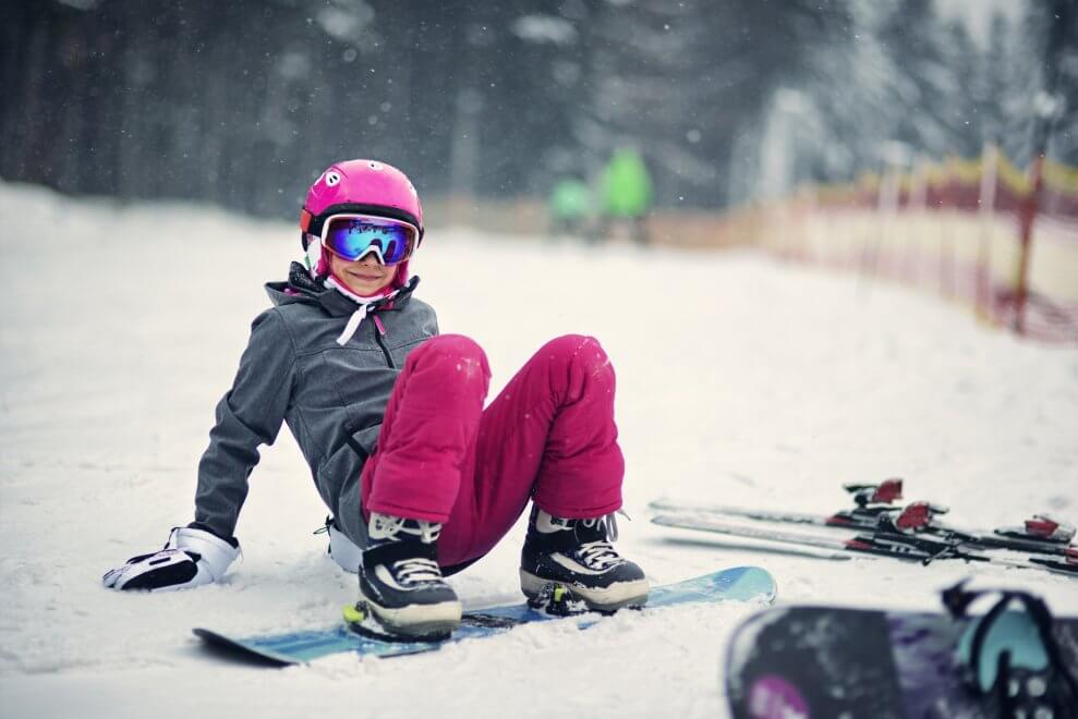 A girl learns how to snowboard.