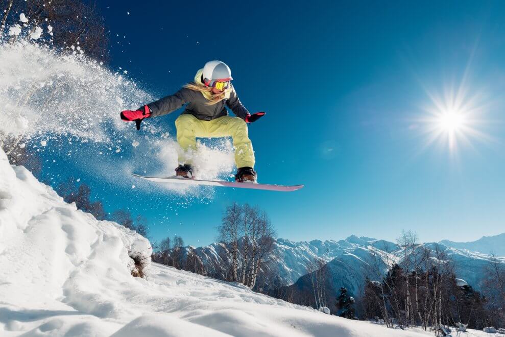A woman snowboards in the mountains on a sunny day.