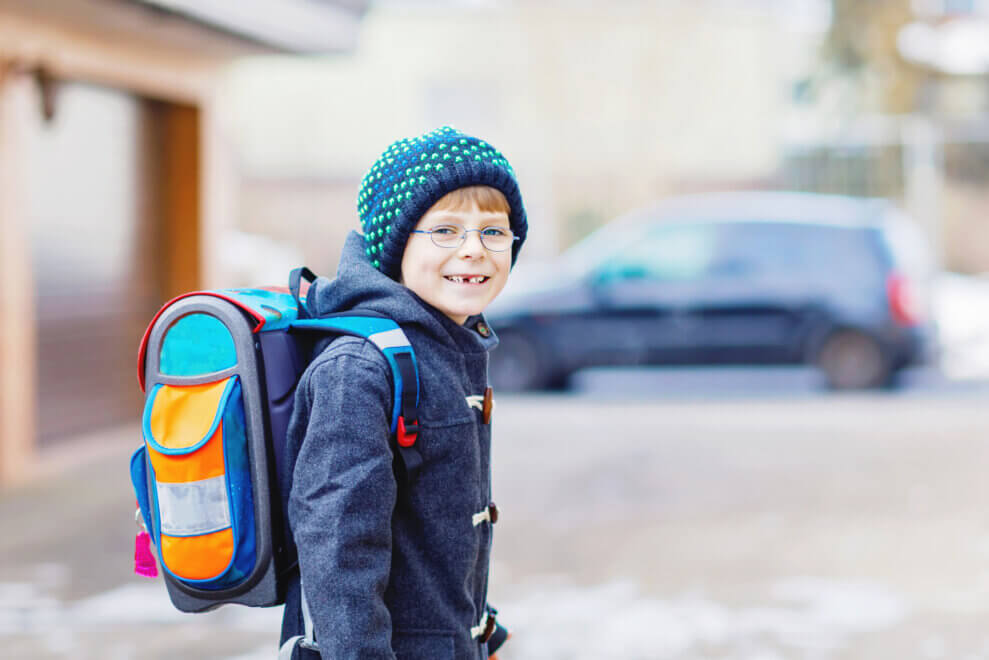 Boy wearing a backpack and a toque walks to school