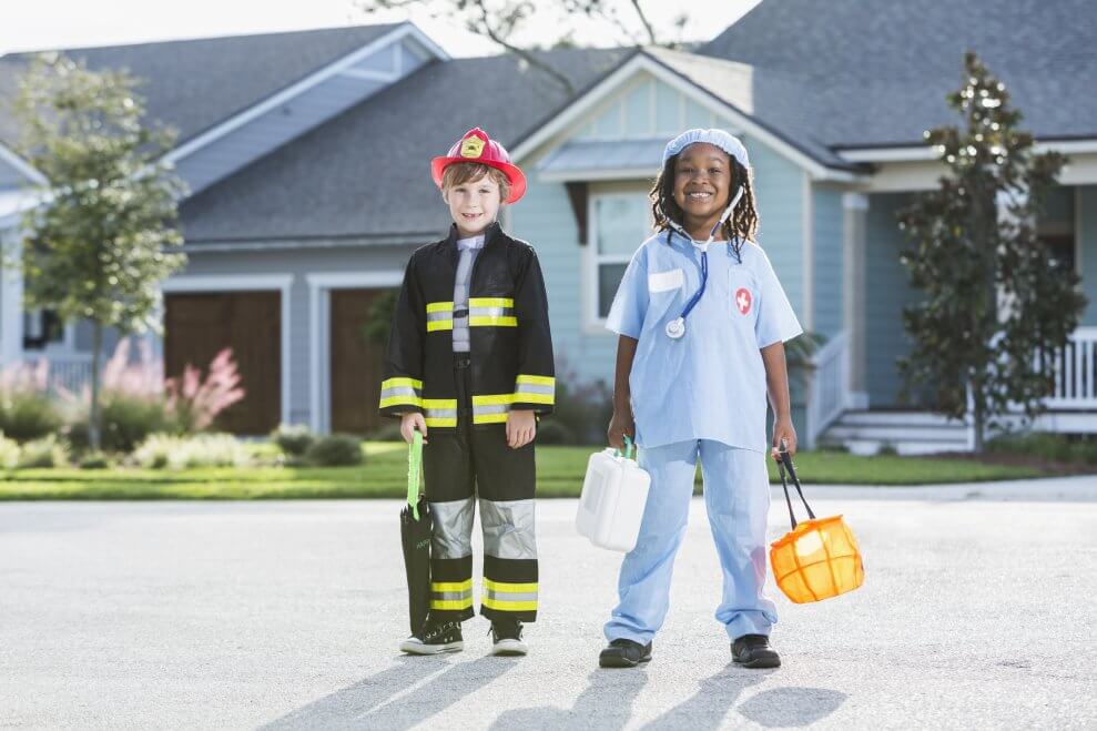 Two children are dressed up for Halloween, one as a firefighter and the other as a doctor.