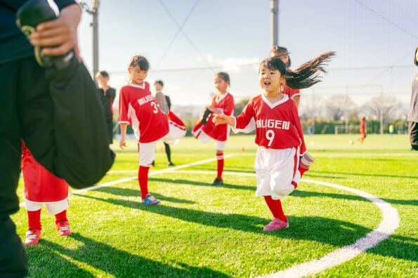 Led by their coach, a children's soccer team stretches before a game.