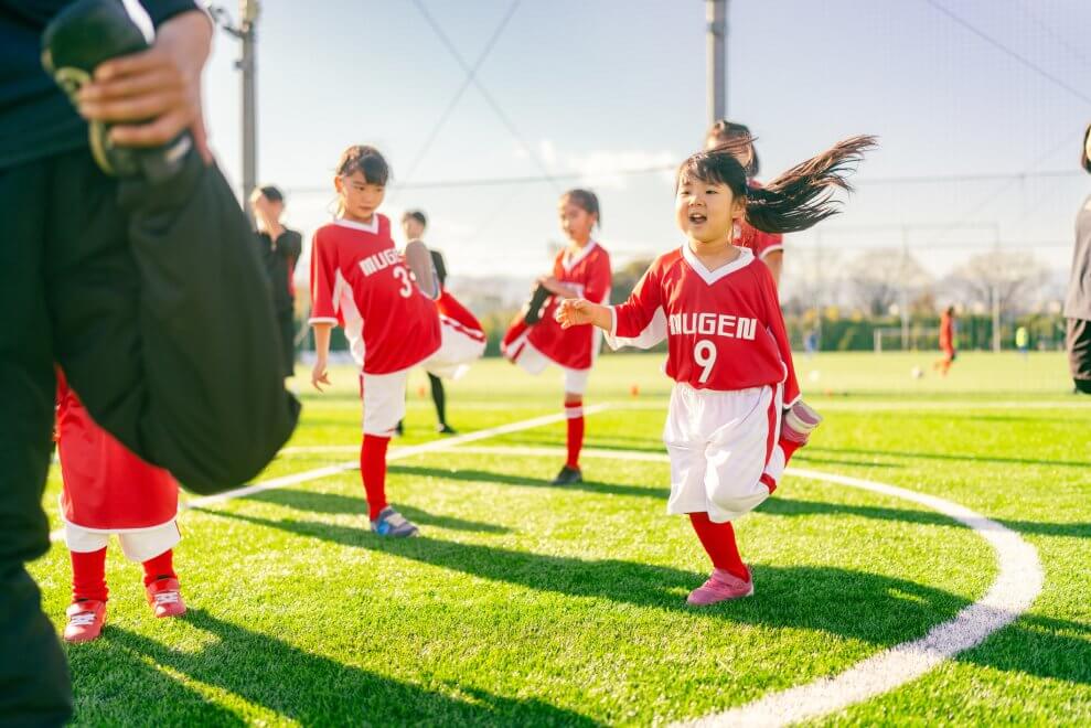 Led by their coach, a children's soccer team stretches before a game.