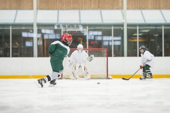 A young hockey player takes a shot on goal in a hockey arena.