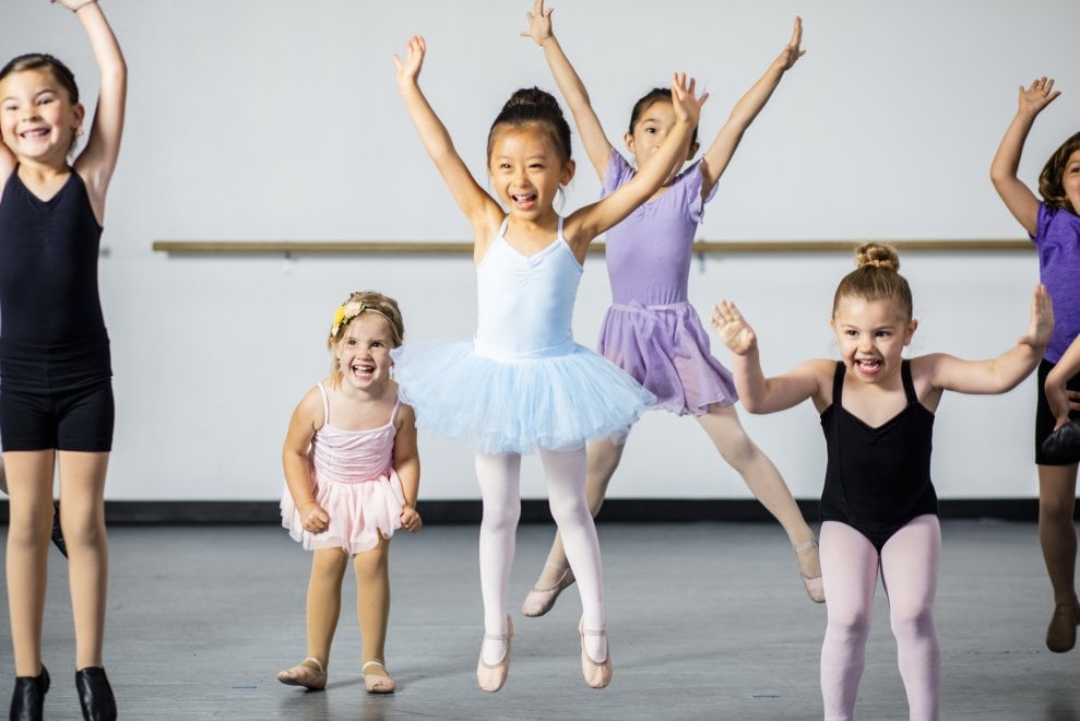 A diverse young group of students practice in musical theatre and ballet combo dance class