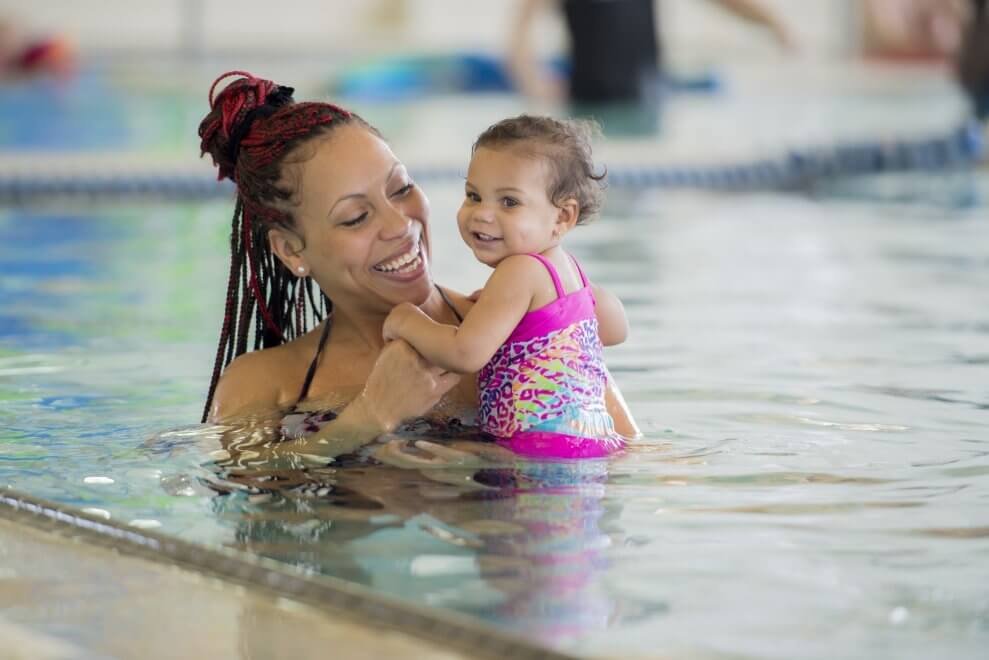 A mom and her baby daughter participate in an aquafit class in a swimming pool.