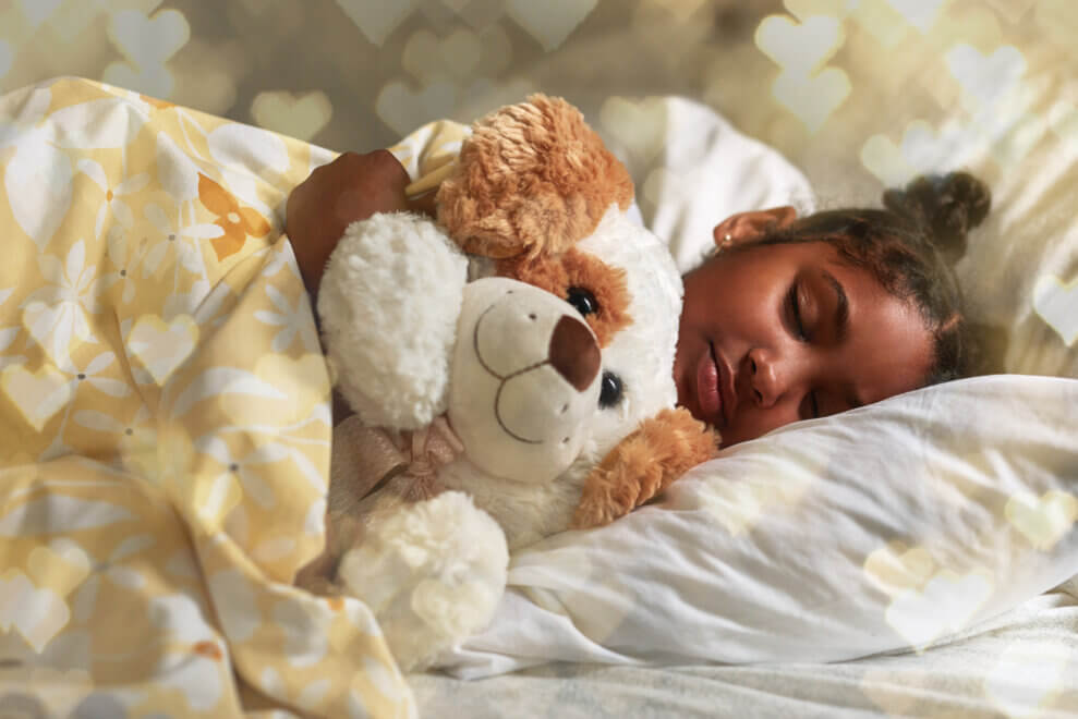 A girl sleeps in bed clutching her stuffed puppy dog