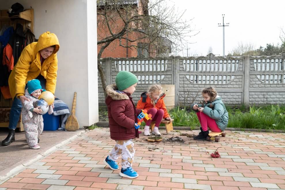 Four children of varying ages play outdoors at a childcare centre.