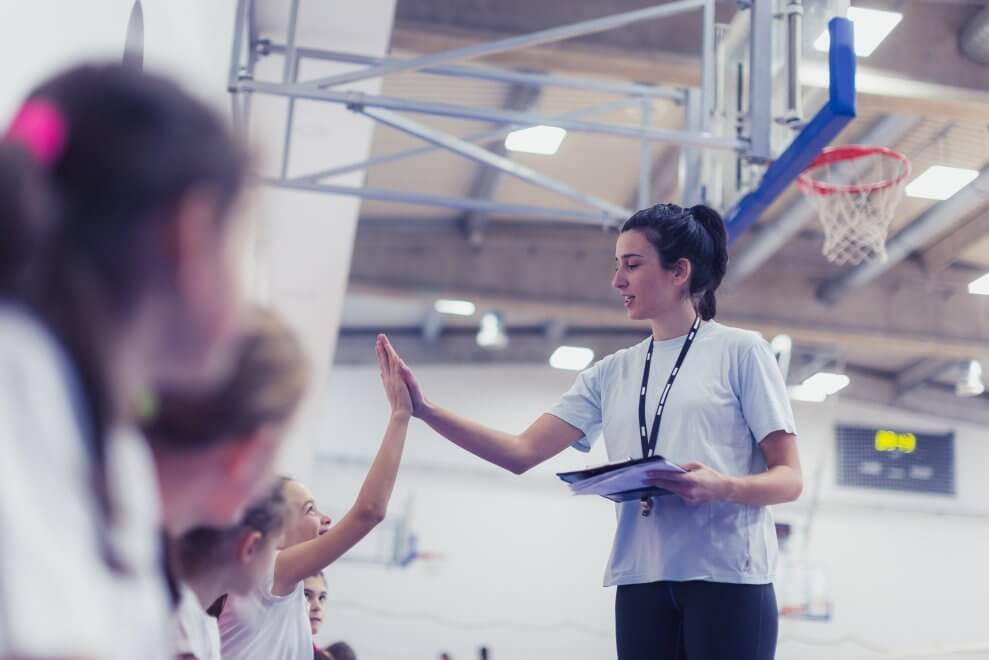 A coach high-fives athletes on her volleyball team.