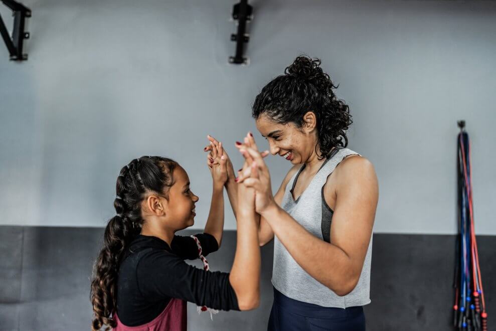 A mom and her daughter high-five after working out together at a boxing gym.