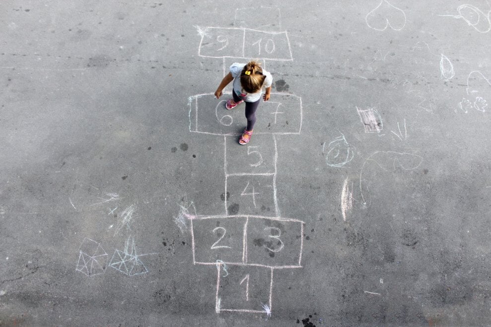 A girl plays hopscotch on the playground at recess.