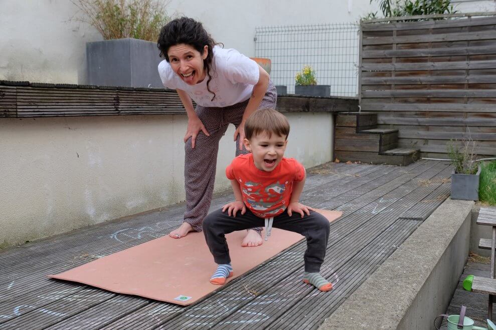 A mother and her toddler son do lion's pose.