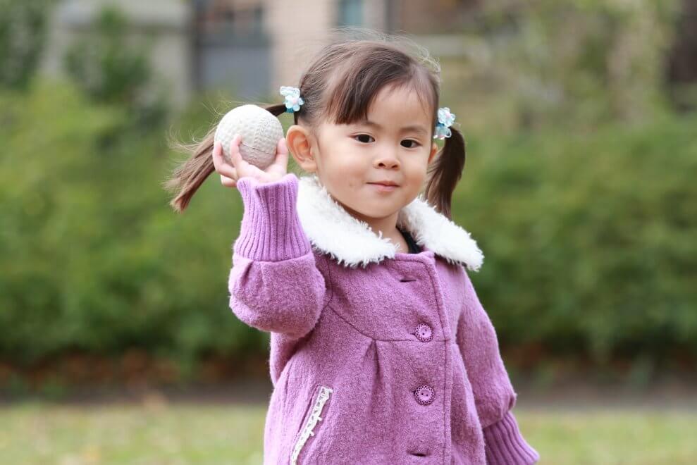 A young girl throws a ball, demonstrating a fundamental movement skill.