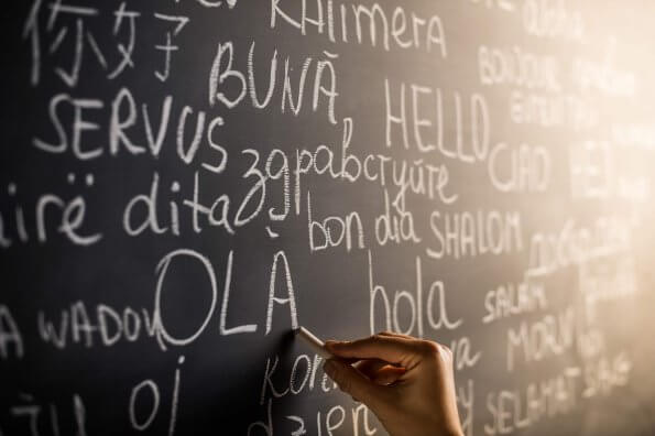 person writes on chalkboard in various languages