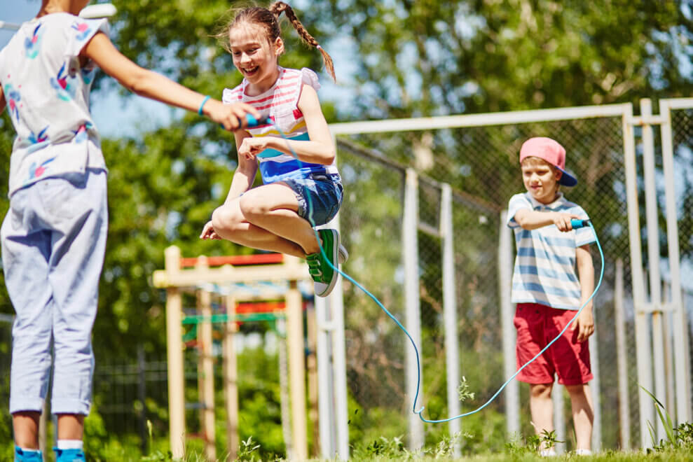 Three kids jump rope at a playground