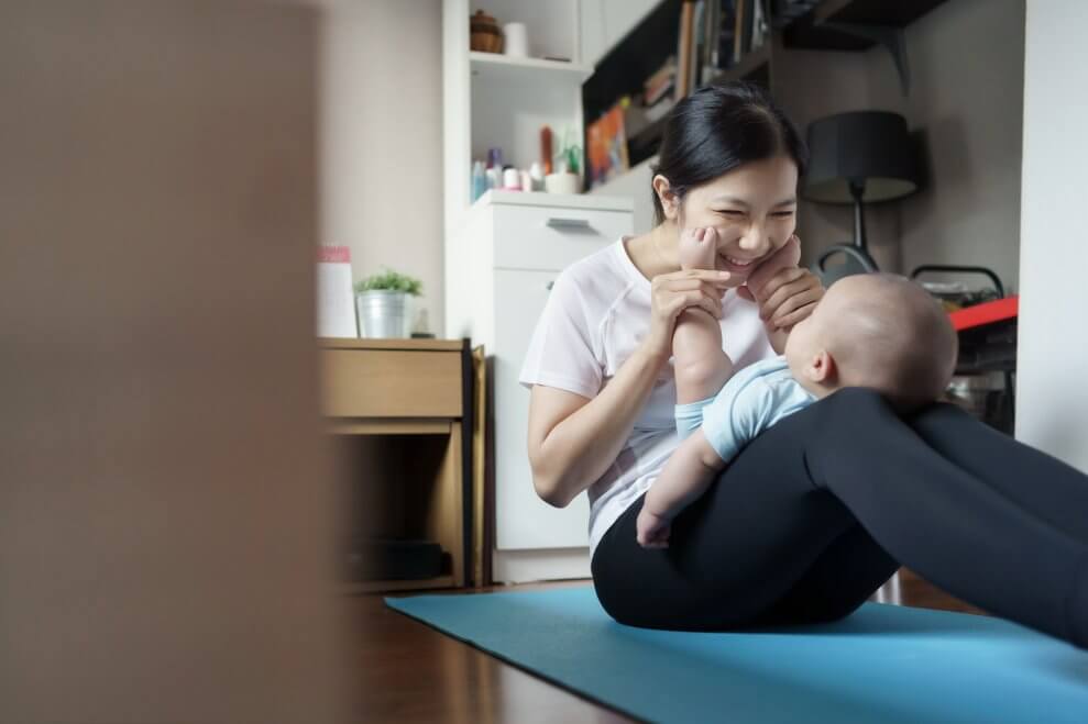 mom-and-baby-on-yoga-mat-as-mom-stretches-baby-legs