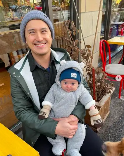 Patrick Chan smiles while holding his son, Olivier.