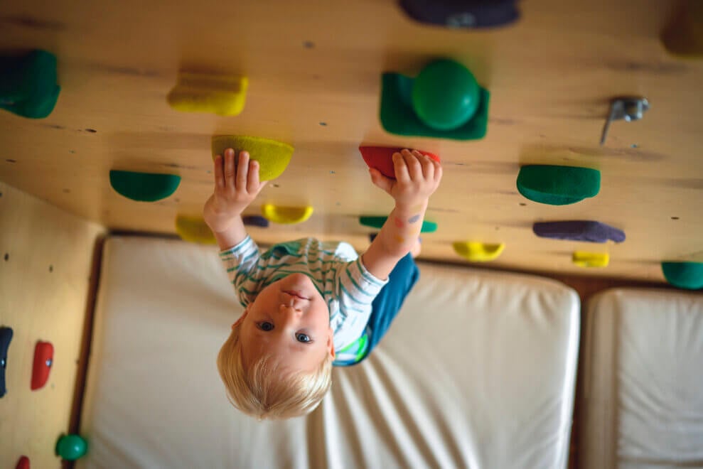 Toddler climbing up climbing wall at home