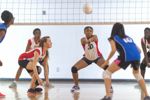 During volleyball game, teenage girl prepares to bump the ball to her teammate