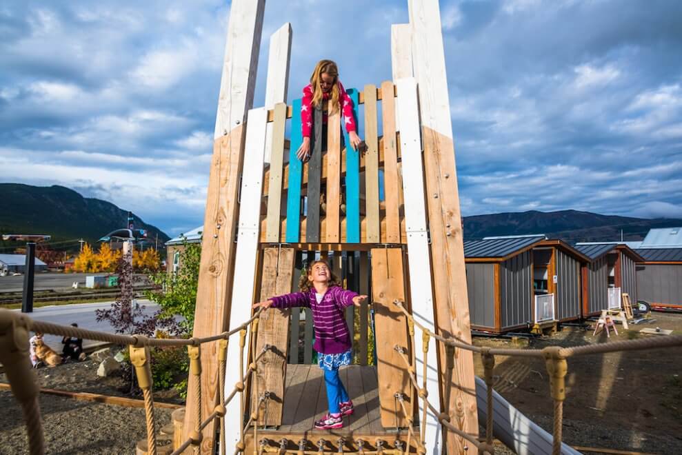 Two girls play on a wooden tower section of the playground at the Carcross Commons in the Yukon.