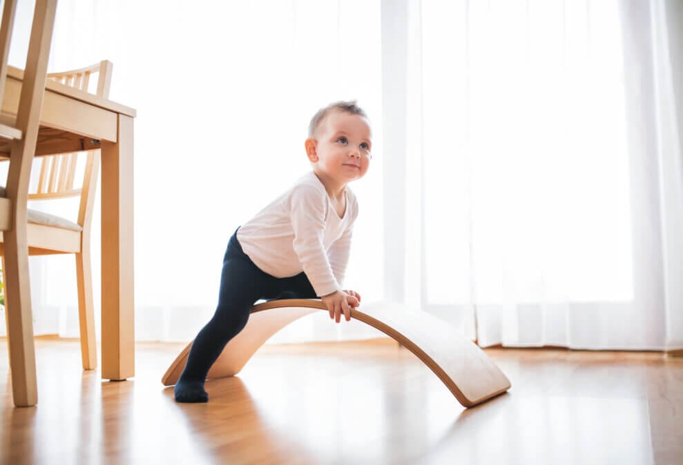 Toddler climbs on top of balance board in the kitchen