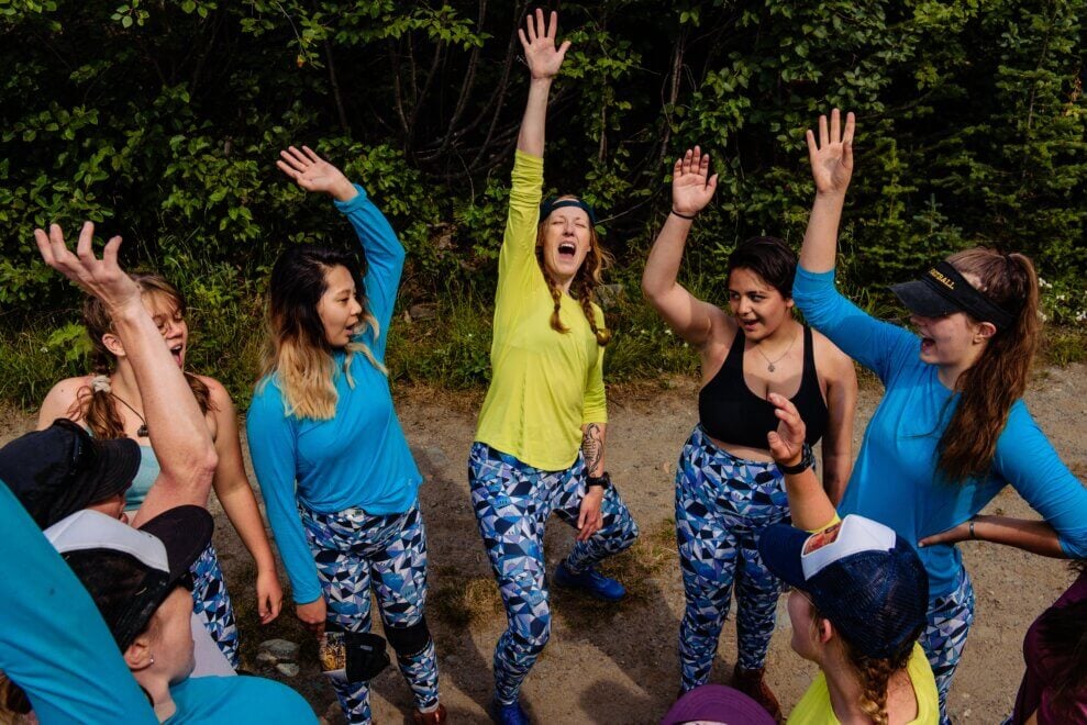 Circle of teen participants cheers along with Girl in the Wild founder Kim McMullen