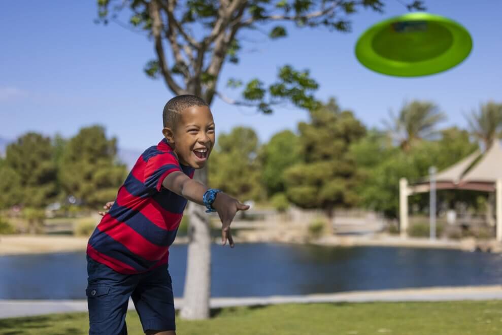 A boy tosses a Frisbee at a park—one fun camping activity kids can play.