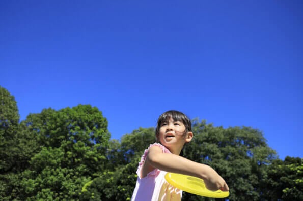 Girl tossing a Frisbee into the air on a summer day