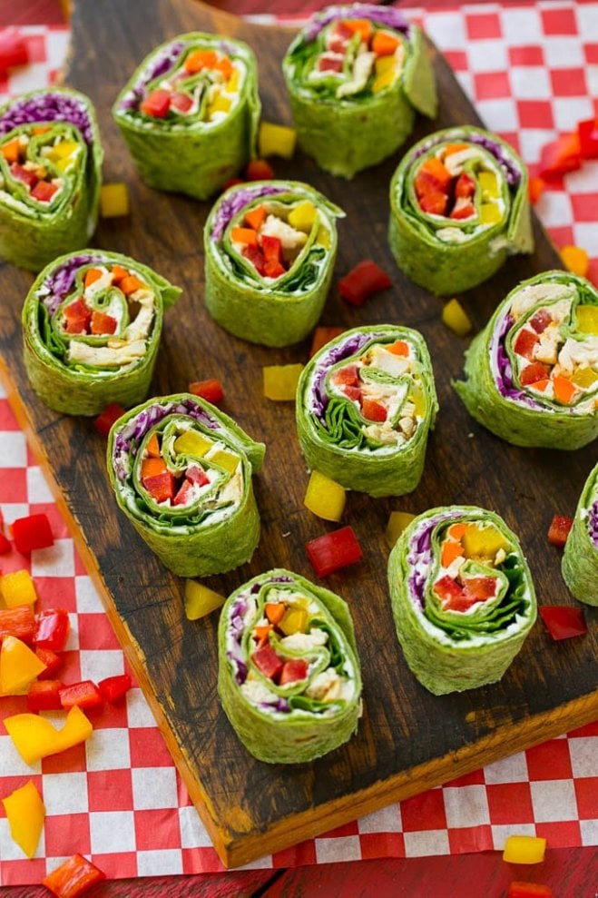 Veggie pinwheel wraps sit laid out on a wooden cutting board.