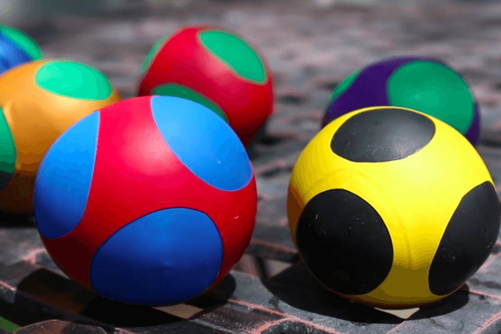 Five multicoloured squishy balls made of balloons and flour sit on a patio table