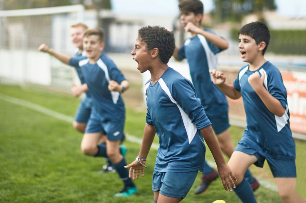 Preteen boys' soccer team runs onto the field, cheering