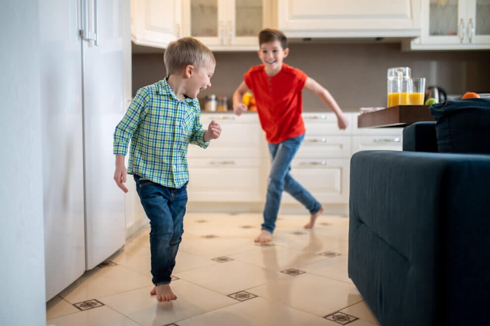 One brother chases the other around the kitchen