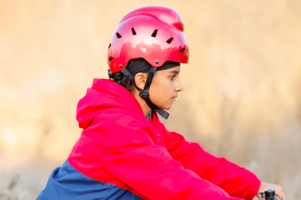 A Sikh boy rides a bike while wearing a helmet that accommodates his turban.