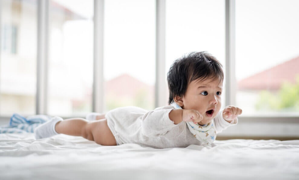 A baby lies on her stomach on a blanket.