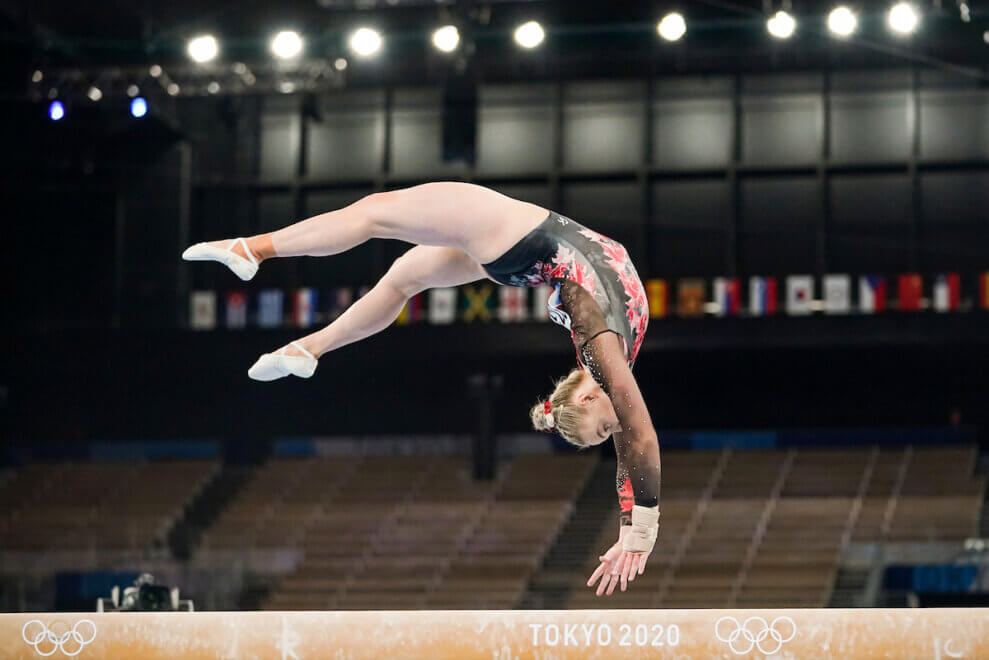 Olympian Ellie Black does a flip in the air on the balance beam.