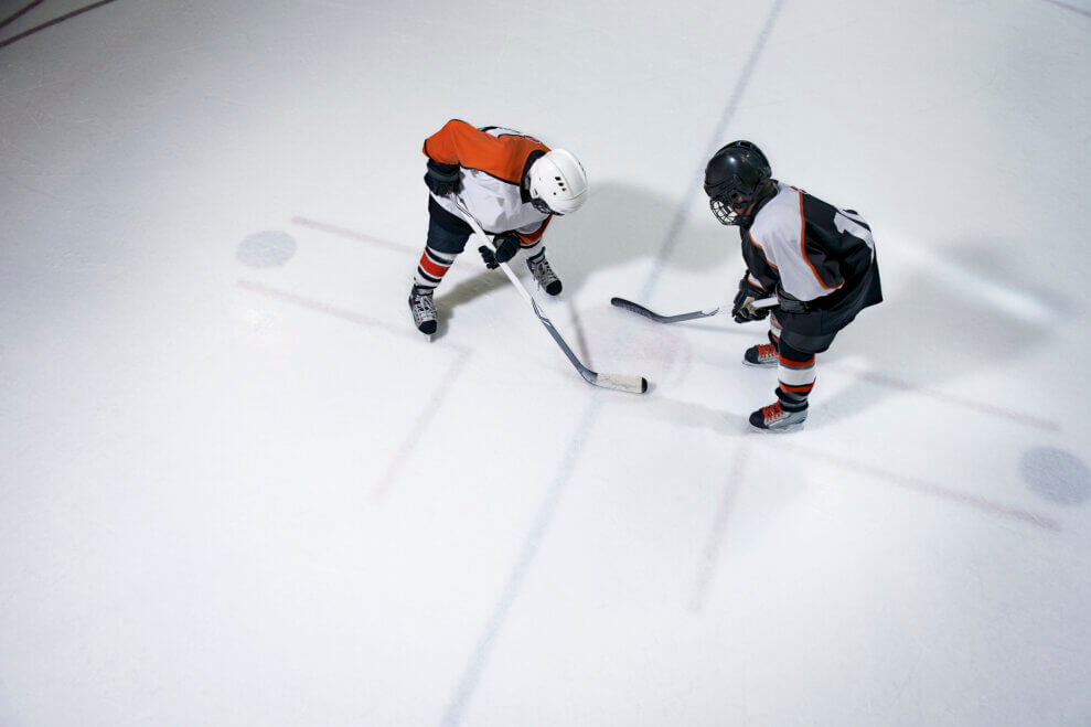 Two child hockey players face-off on the ice.