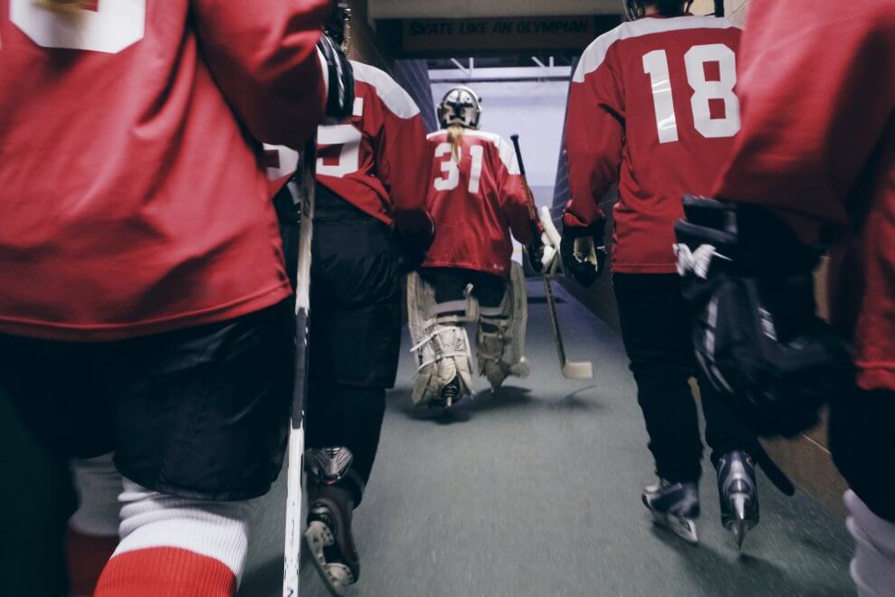 A women's hockey team walks down a hallway to head out onto the ice.
