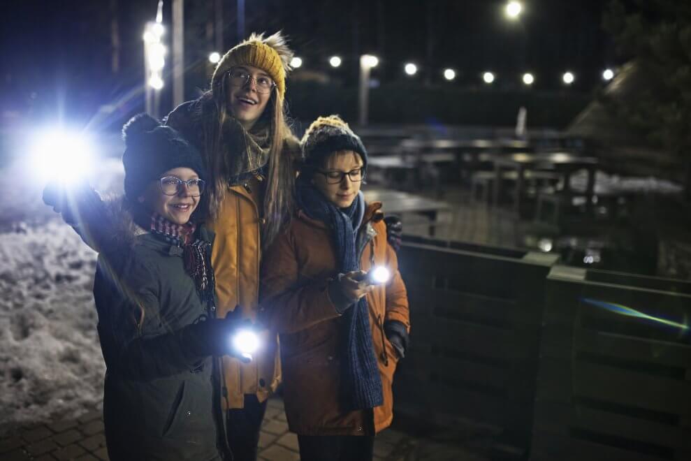 A mom and her two kids play flashlight tag in the dark.